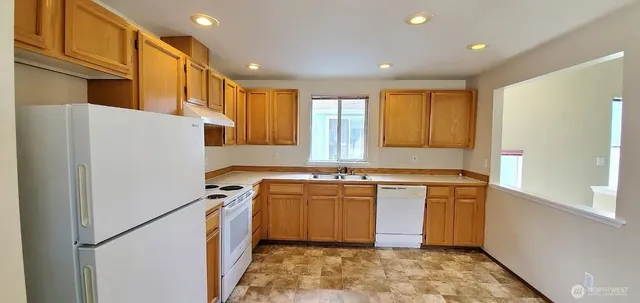 a kitchen with stainless steel appliances granite countertop a refrigerator a stove and a sink