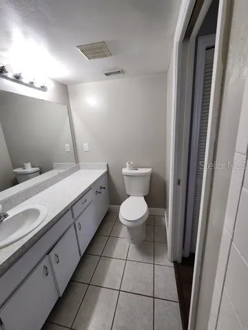 a bathroom with a granite countertop sink a toilet a mirror and shower