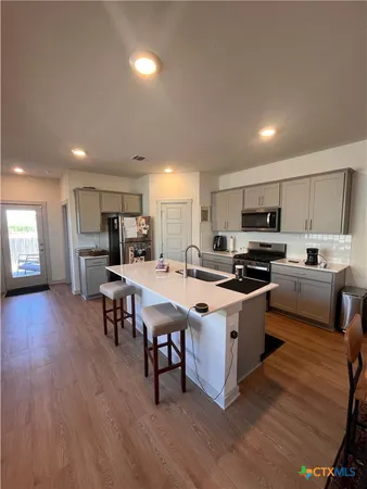 a kitchen with stainless steel appliances kitchen island granite countertop a sink a stove a refrigerator cabinets and a dining table