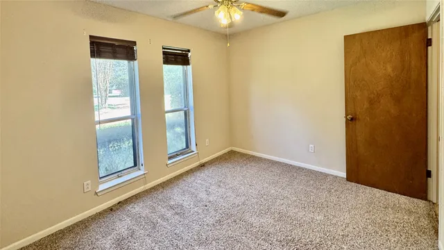 an empty room with a window and a ceiling fan