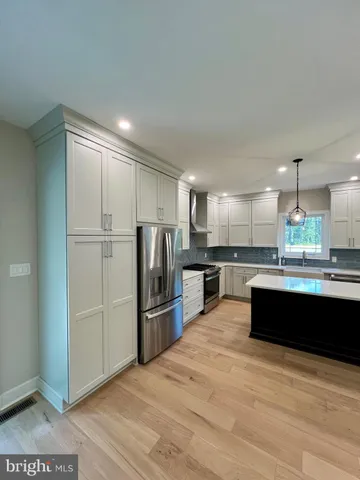 a large kitchen with stainless steel appliances kitchen island granite countertop a sink and a stove