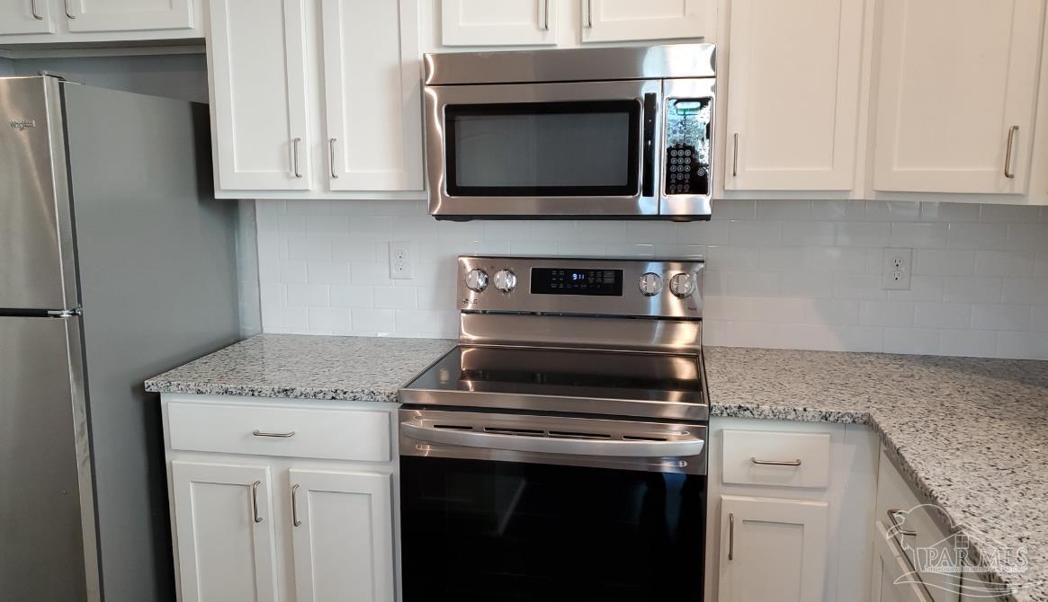 9822 Utopia Drive, Unit E Pensacola, FL 32514 - Photo 11 of 13 a kitchen with granite countertop white cabinets and stainless steel appliances