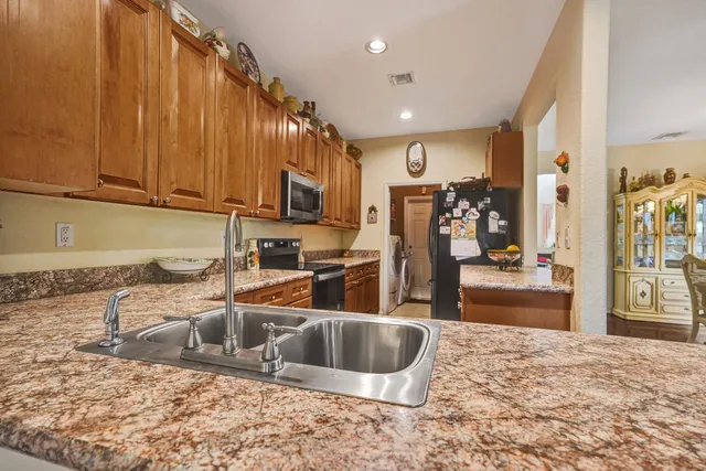a kitchen with stainless steel appliances granite countertop a sink a stove and a refrigerator with wooden floor