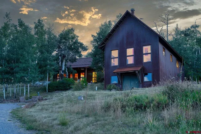 a view of house with yard and trees in the background