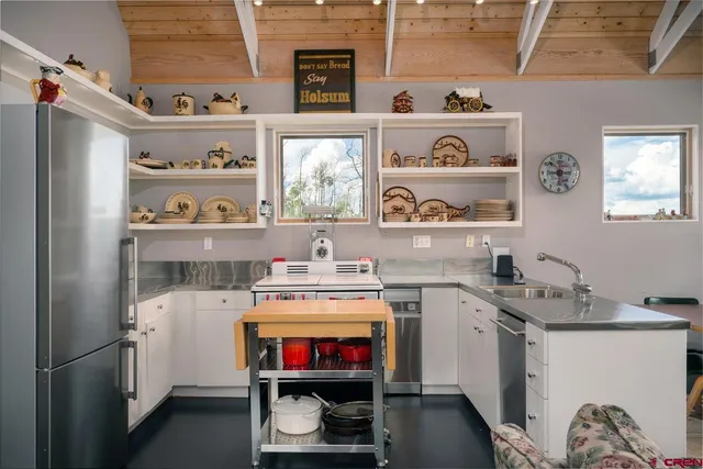a utility room with stainless steel appliances a stove a sink and a refrigerator