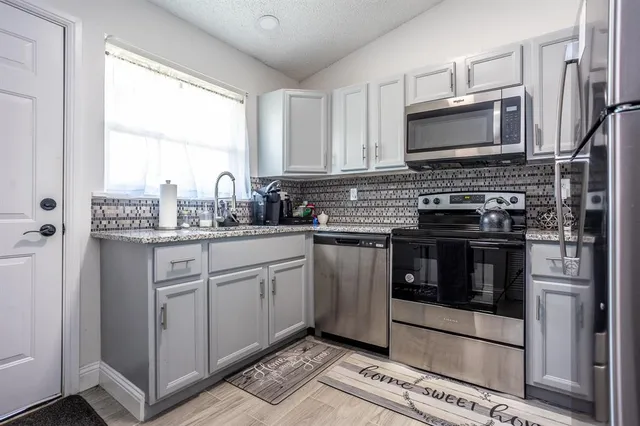 a kitchen with stainless steel appliances a stove a sink and a microwave