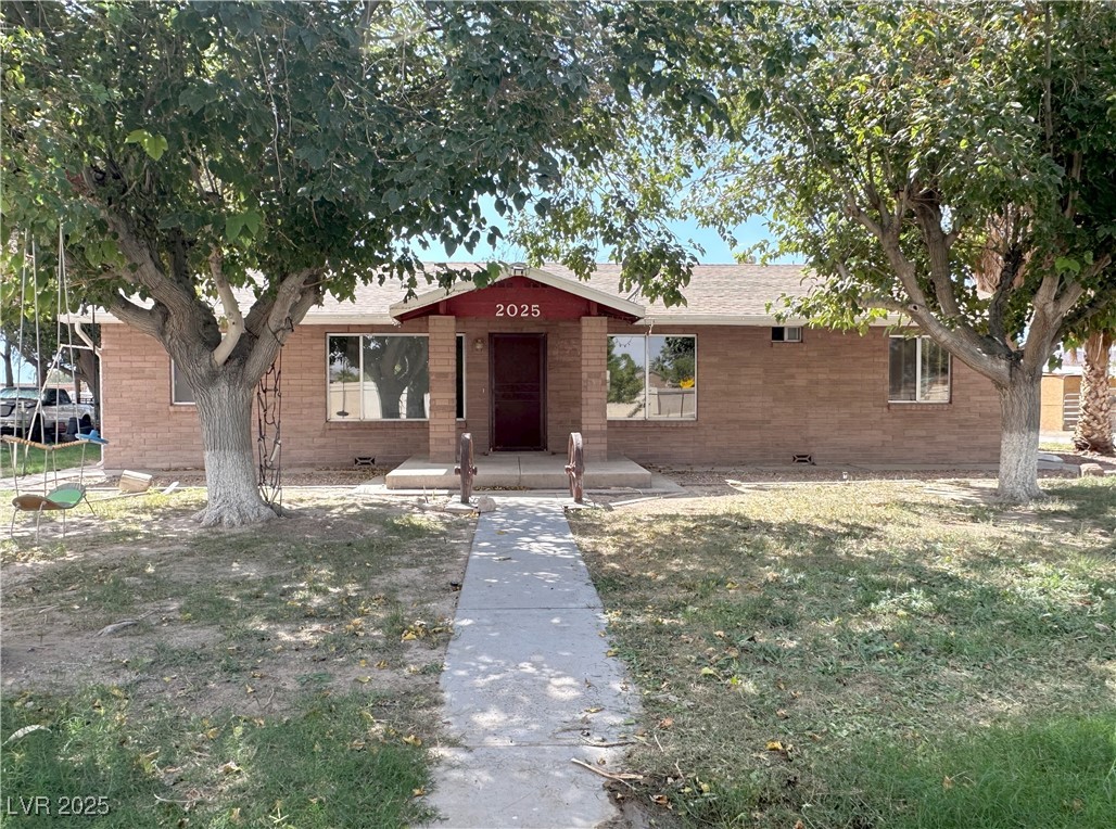 2025 Whipple Avenue Logandale, NV 89021 - Photo 4 of 44 View of front of house with a front lawn, brick siding, and mature trees