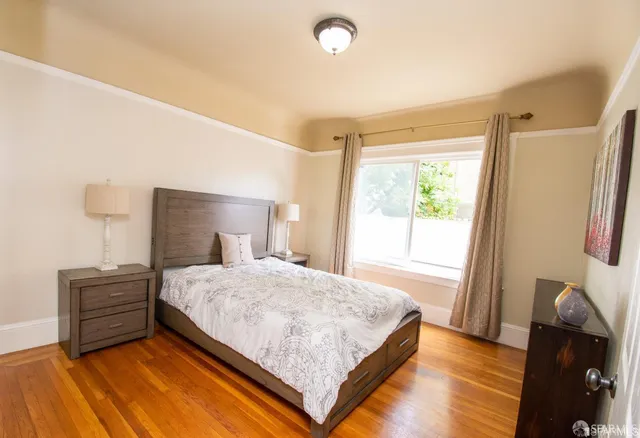 a bedroom with a bed window and a wooden floor