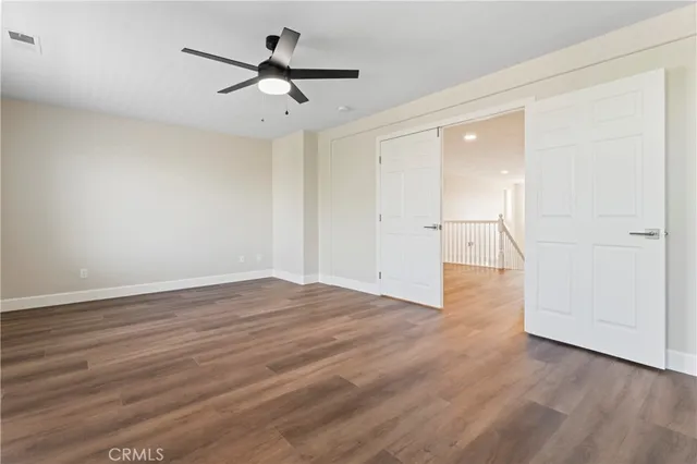 an empty room with wooden floor and a ceiling fan