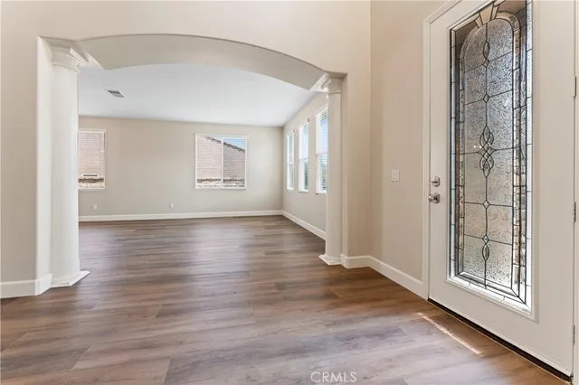 an empty room with wooden floor and windows