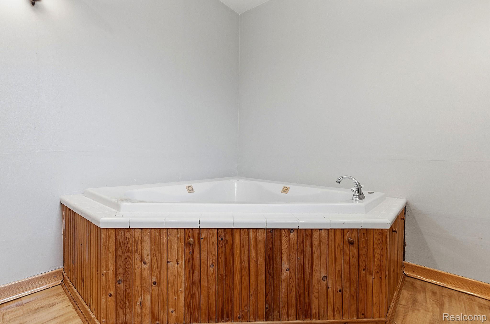 5852 Beech Daly Road Taylor, MI 48180 - Photo 12 of 29 Corner jetted bathtub with a wood-panel surround and white tile deck