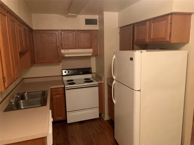 a white refrigerator freezer and a stove sitting inside of a kitchen
