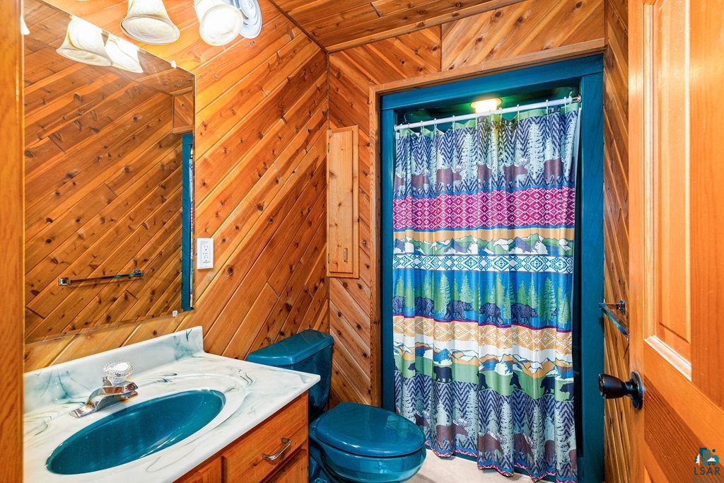 5370 Ugstad Road Hermantown, MN 55811 - Photo 14 of 68 Wood paneling with diagonal application, wood-finish vanity with drawer storage, integrated basin, and a wall-mounted mirror