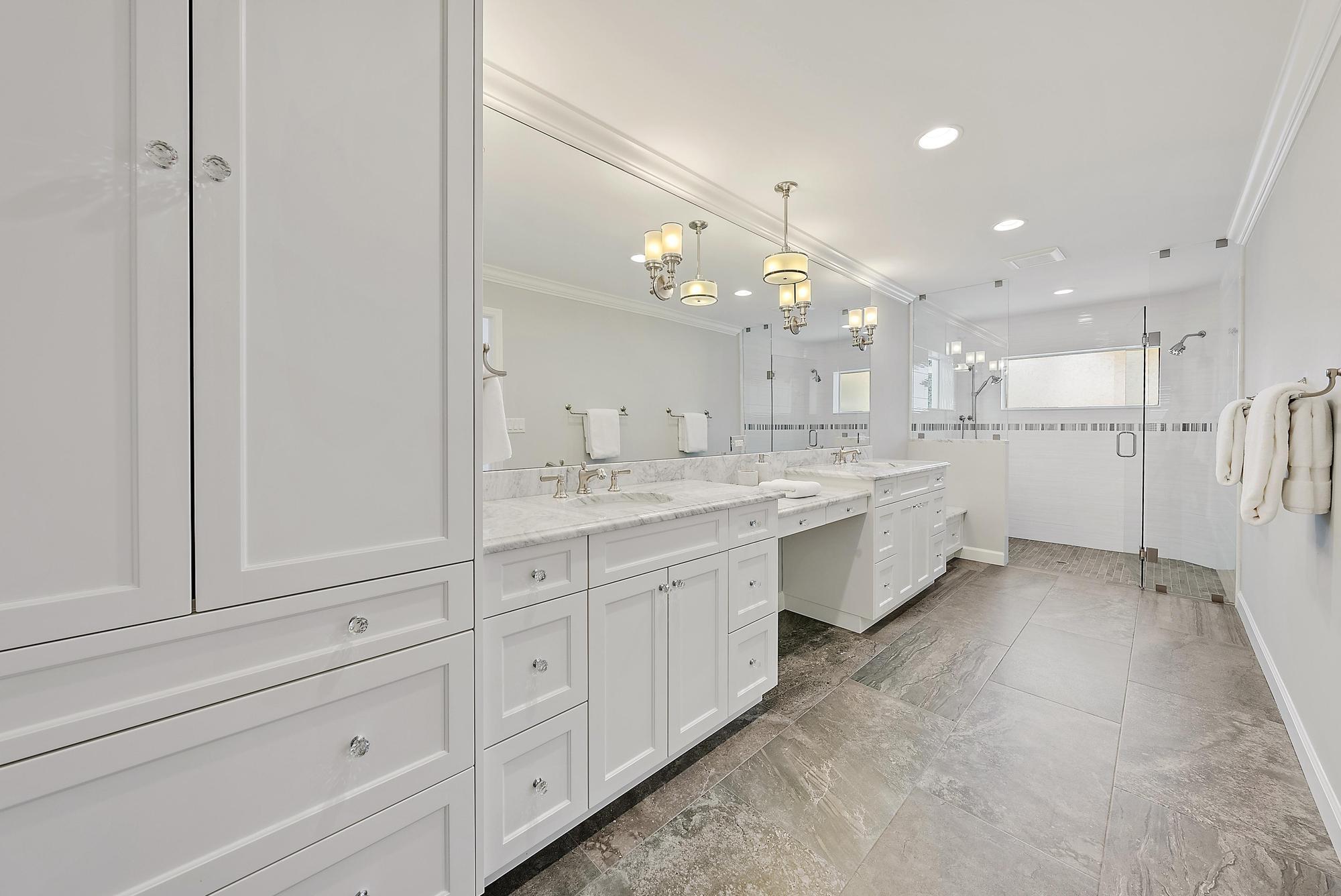 1051 Gulfstream Way Singer Island, FL 33404 - Photo 17 of 49 a large white bathroom with a large mirror vanity and shower