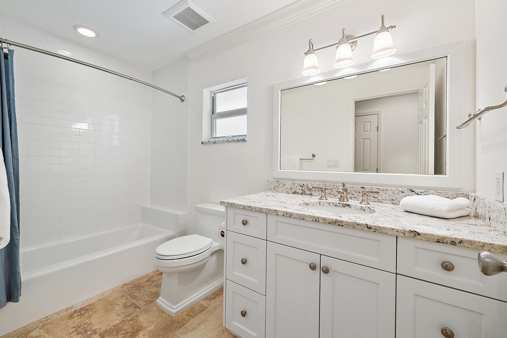 1051 Gulfstream Way Singer Island, FL 33404 - Photo 26 of 49 a bathroom with a granite countertop sink a toilet and a large mirror