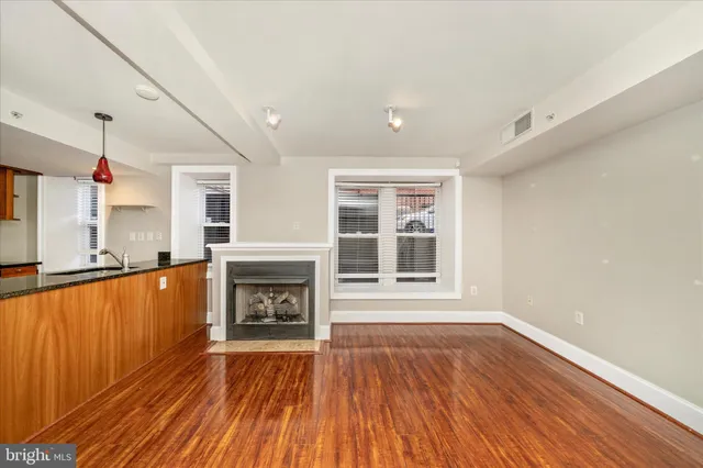 a view of an empty room with wooden floor fireplace and a window