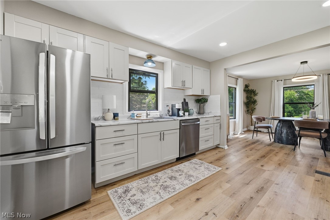 951 Bey Road Akron, OH 44312 - Photo 13 of 34 Kitchen featuring white shaker cabinetry, stainless steel appliances, light-toned wood-finish flooring, and a white subway tile backsplash