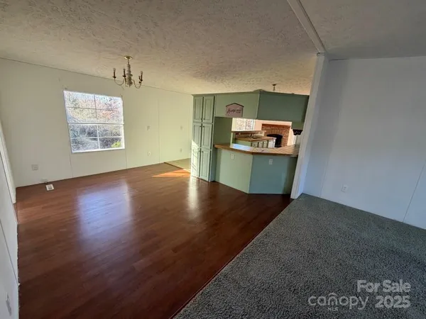 an empty room with wooden floor kitchen view and a window