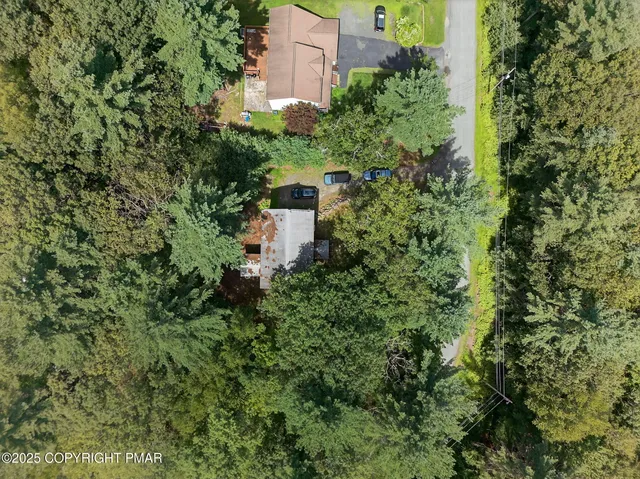 an aerial view of residential house with outdoor space and trees all around
