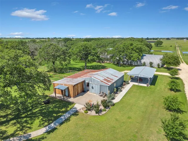 an aerial view of residential houses with outdoor space and trees