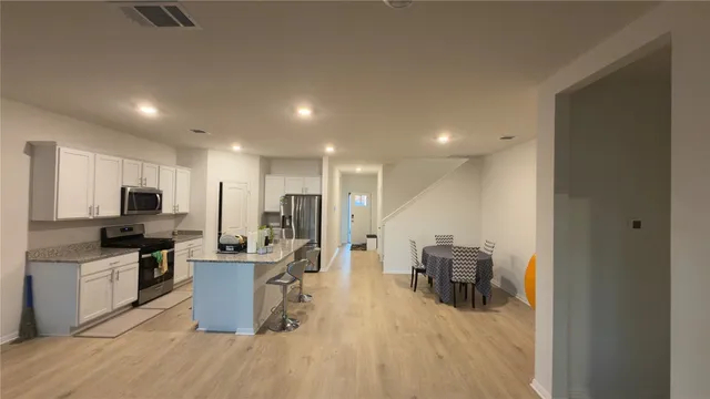a view of a kitchen with kitchen island stainless steel appliances refrigerator stove microwave and cabinets