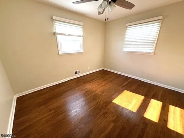 a view of an empty room with window and wooden floor
