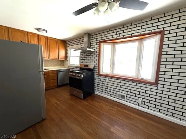 a kitchen with stainless steel appliances granite countertop a sink a stove a refrigerator wooden floor and cabinets