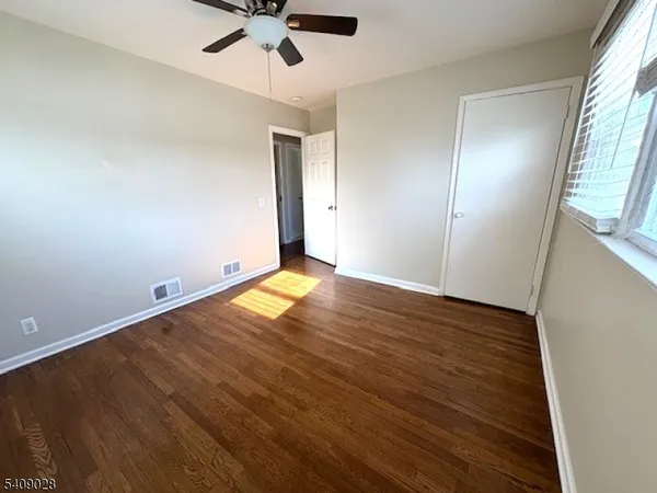 an empty room with wooden floor fan and windows