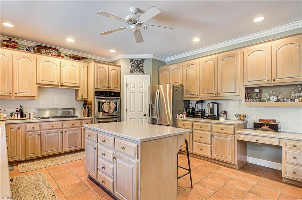 5401 Leytonstone Court Oak Ridge, NC 27310 - Photo 13 of 41 Abundance of cabinets, solid surface countertops, tile flooring, center island and desk area.