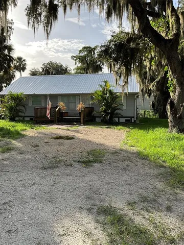a view of a house with a yard and palm trees