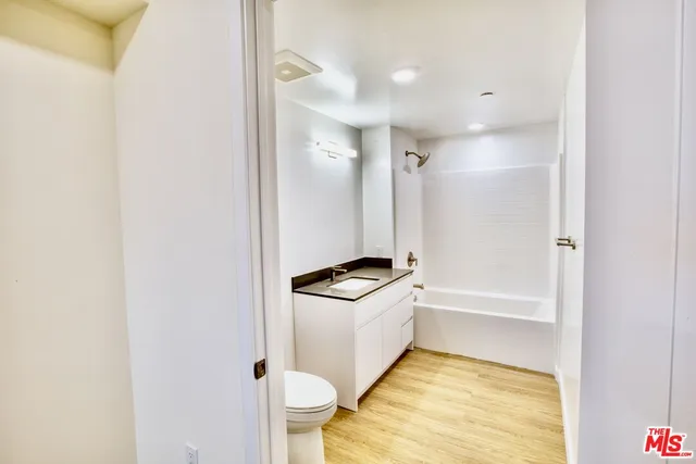 a bathroom with a tub sink vanity and toilet
