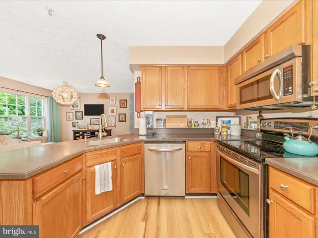 a open kitchen with stainless steel appliances granite countertop a stove top oven a sink dishwasher and white cabinets with wooden floor