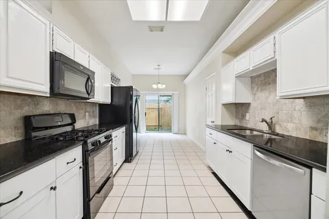 a kitchen with stainless steel appliances granite countertop a sink a stove top oven a chimney and cabinets