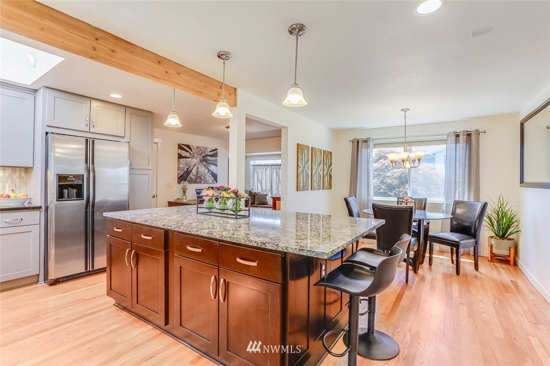 3522 Northeast 10th Place Renton, WA 98056 - Photo 8 of 34 a kitchen with stainless steel appliances granite countertop a refrigerator a sink dishwasher a dining table and chairs with wooden floor
