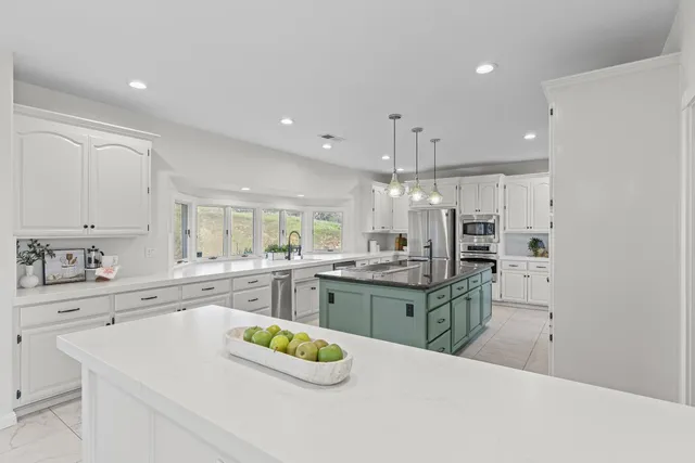 a kitchen with stainless steel appliances kitchen island granite countertop a sink and cabinets