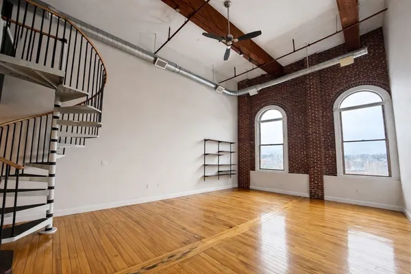 a view of empty room with wooden floor and fan