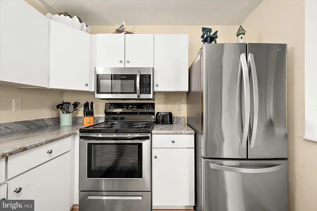a kitchen with appliances a refrigerator and cabinets