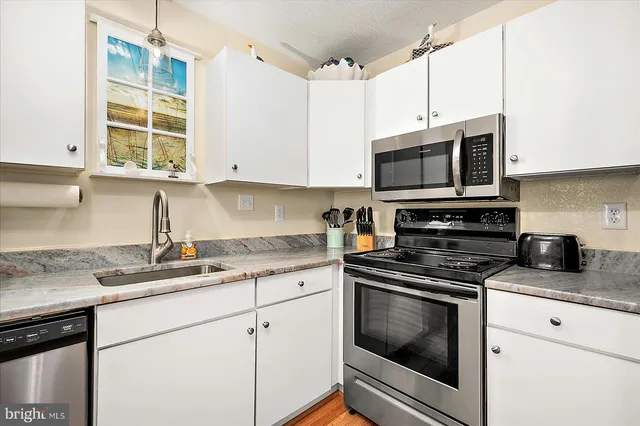a kitchen with granite countertop cabinets stainless steel appliances and a sink