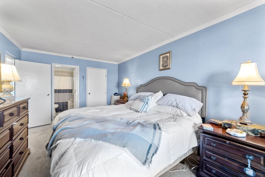 100 Cove Way, Unit 608 Quincy, MA 02169 - Photo 17 of 26 a bedroom with a bed and a lamp on dresser