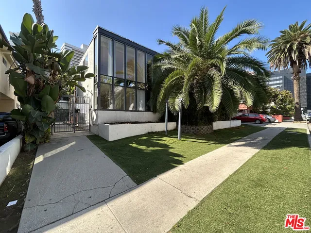 a view of a house with a yard and palm trees
