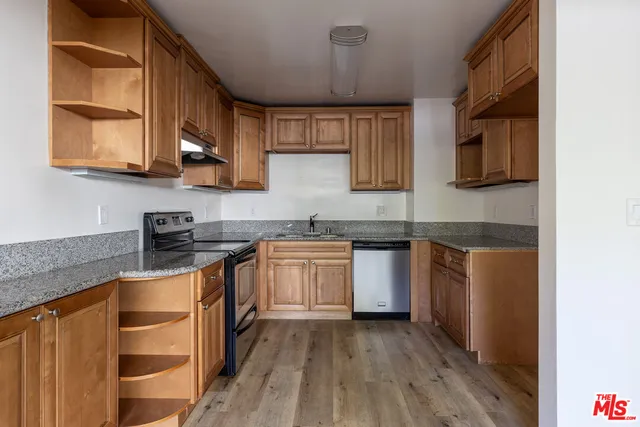 a kitchen with stainless steel appliances granite countertop wooden cabinets a stove top oven a sink and dishwasher