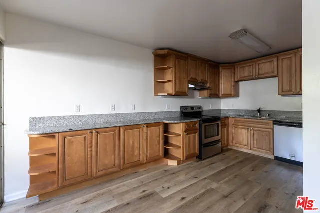 a kitchen with granite countertop a stove top oven a sink dishwasher and white cabinets with wooden floor