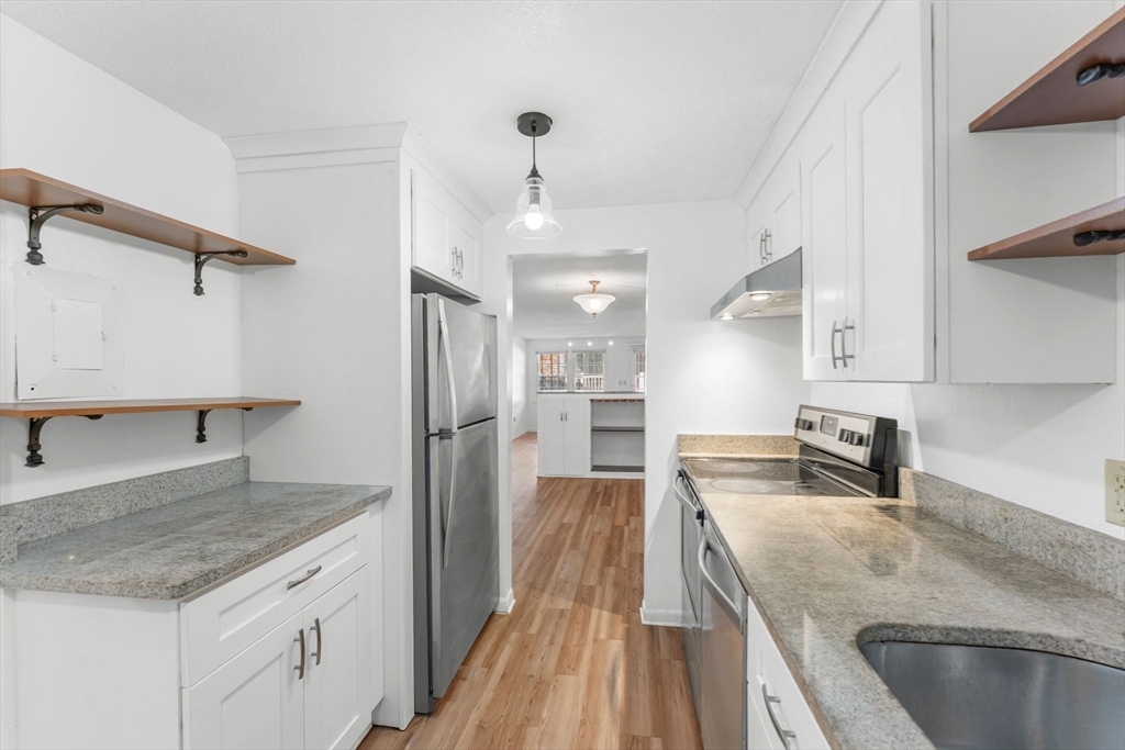 5 Elm Street, Unit 1 Acton, MA 01720 - Photo 13 of 30 a kitchen with kitchen island a counter top space a sink stainless steel appliances and cabinets