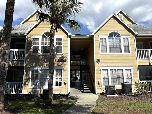 a view of a brick house with many windows next to a yard