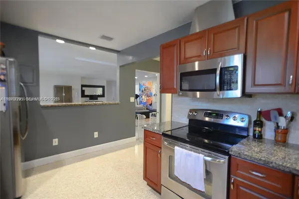 a kitchen with stainless steel appliances granite countertop a stove a sink and a microwave