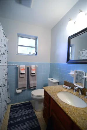 a bathroom with a granite countertop toilet sink and mirror