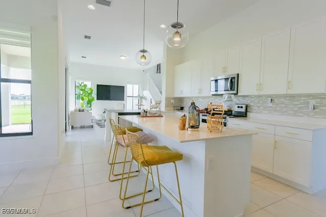 a view of kitchen with stainless steel appliances granite countertop dining room cabinets and chandelier
