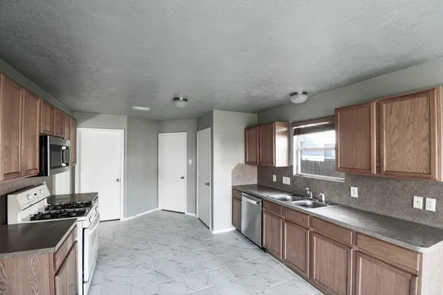 a large kitchen with stainless steel appliances granite countertop a sink stove and refrigerator