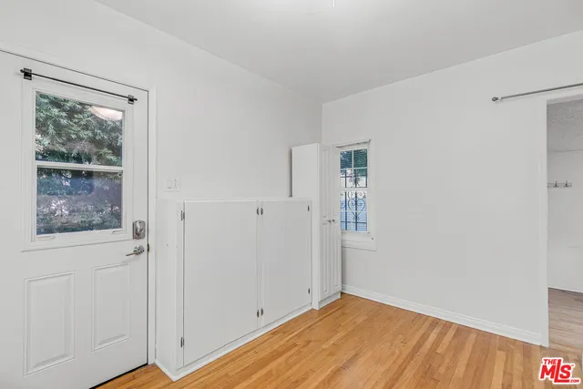 a view of an empty room with wooden floor and a window