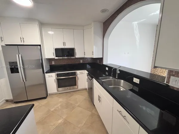 a kitchen with granite countertop stainless steel appliances a sink a stove and a refrigerator